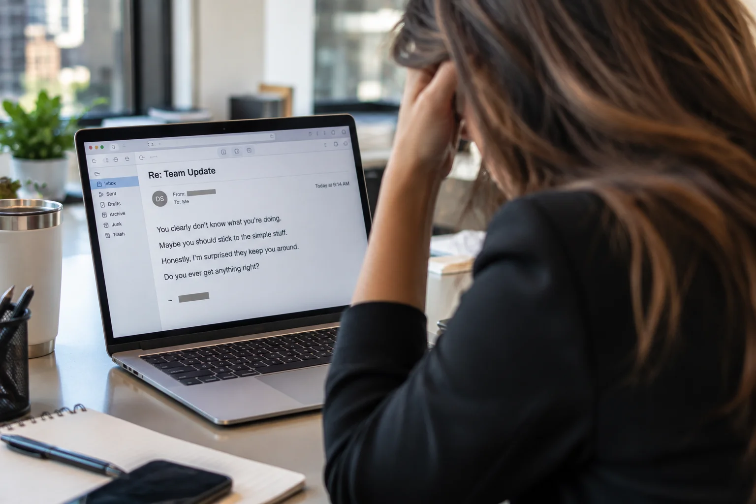 Employee reading a demeaning work email on her laptop in an office